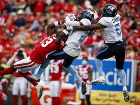Toronto Argonauts' Treston Decoud, centre, and Chris Edwards, right, battle for a pass meant for Calgary Stampeders' Josh Huff during second half CFL football action in Calgary, Saturday, Aug. 7, 2021.