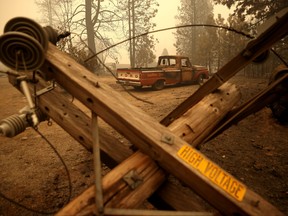A partially burned truck sits parked near a downed electrical power pole after the Dixie Fire moved through the area on Aug. 11, 2021 in Greenville, Calif.