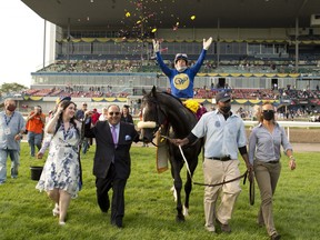 Jockey Irad Ortiz Jr., tosses flowers into the air as breeder Mitch Kursner in suit) leads Safe Conduct into the winners circle after yesterday’s Queen’s Plate victory at Woodbine. Kursner’s late grandfather introduced him to the horses as a youngster.