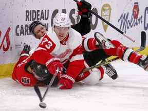 Adam Erne pokes the puck with Mike Reilly  (bottom) and Brady Tkachuk trying to defend in the second period as the Ottawa Senators take on the Detroit Red Wings in NHL action at the Canadian Tire Centre in Ottawa on Feb. 29, 2020.