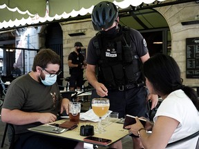 A policeman checks the health pass of customers at a bar in Bordeaux, southwestern France, on August 11, 2021.