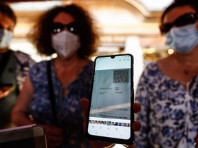 A woman shows her health pass as she arrives at a restaurant in Mont-Saint-Michel, in Normandy, France, July 22, 2021.
