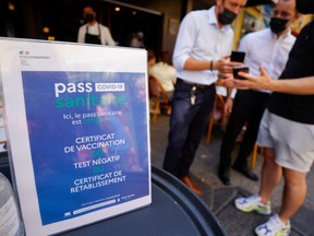 A man shows his COVID-19 health pass at a restaurant as France brings on tougher restrictions where a proof of immunity will now be required to access most public spaces and to travel by inter-city train, in Nice, France, Aug. 9, 2021.