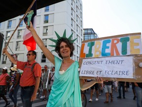 A protester dressed as the Statue of Liberty holds a placard reading "Liberty, free and informed consent" during a demonstration called by the French nationalist party "Les Patriotes" (The Patriots) against France's restrictions, including a compulsory health pass, to fight the COVID-19 outbreak, in Paris, Aug. 14, 2021.