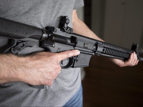 A restricted gun licence holder holds a AR-15 at his home in Langley, B.C. on May 1, 2020.