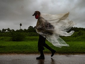 A man walks under the rain in Batabano, Mayabeque province, about 60 km south of Havana, on Aug. 27, 2021, as Hurricane Ida passes through eastern Cuba.
