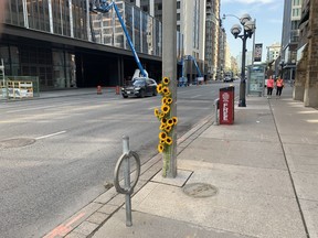 Flowers taped to a pole at the scene of a fatal collision between a cyclist and a dump truck on Avenue Rd. just north of Bloor St. W. are seen Thursday, Aug. 19, 2021.
