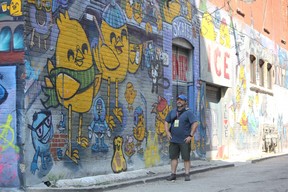 Tour Guys owner Jason Kucherawy checks out some work by artist Uber5000 along Graffiti Alley in Toronto. IAN SHANTZ/TORONTO SUN