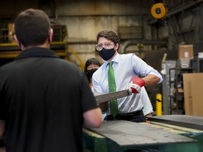 Liberal Leader Justin Trudeau (right) handles a piece of steel before he announces green incentives towards climate change at a campaign stop during the Canadian federal election campaign in Cambridge on