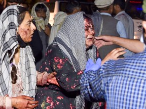Wounded women arrive at a hospital for treatment after two blasts outside the airport in Kabul on Aug. 26, 2021.