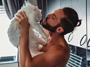 Man kissing his pet cat in the kitchen