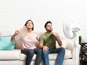 Couple Sitting In Front Of Fan During Hot Weather