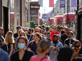Pedestrians, some wearing face coverings due to COVID-19, walk past shops on Oxford Street in central London, England, June 7, 2021.