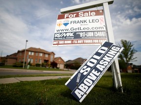 A real estate sign that reads "For Sale" and "Sold Above Asking" stands in front of housing in Vaughan, a suburb in Toronto in this file photo taken on May 24, 2017.
