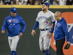 Centre fielder George Springer of the Toronto Blue Jays walks off the field with manager Charlie Montoyo and training personnel after injuring his ankle against the Seattle Mariners at T-Mobile Park on August 14, 2021 in Seattle.