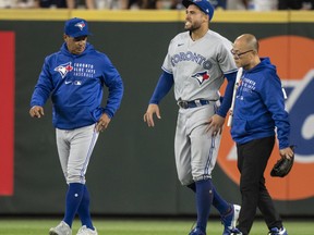 Center-fielder George Springer of the Toronto Blue Jays walks off the field with manager Charlie Montoyo and training personnel after injuring his ankle during the seventh inning of a game against the Seattle Mariners at T-Mobile Park on Aug. 14, 2021 in Seattle, Washington.