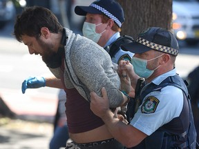 Police officers detain a protestor in Sydney on August 21, 2021, following calls for an anti-lockdown protest rally amid a fast-spreading coronavirus outbreak.
