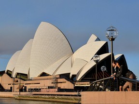 People stand near the Opera House in Sydney on Aug. 14, 2021, as Australia's biggest city announced tighter COVID restrictions including heavier fines and tighter policing to contain a Delta outbreak.