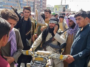 A Taliban fighter is seen surrounded by locals at Pul-e-Khumri on August 11, 2021 after Taliban captured Pul-e-Khumri, the capital of Baghlan province about 200 kms north of Kabul.