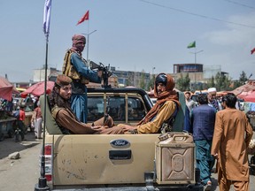 Taliban fighters on a pickup truck move around a market area, flocked with local Afghan people at the Kote Sangi area of Kabul on August 17, 2021.