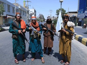 Taliban fighters stand guard along a road near the site of an Ashura procession which is held to mark the death of Imam Hussein, the grandson of Prophet Mohammad, along a road in Herat on August 19, 2021.