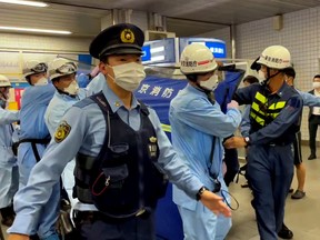 Police escort rescue workers carrying a person through a train station after a knife attack on a train in Tokyo, Japan August 6, 2021.