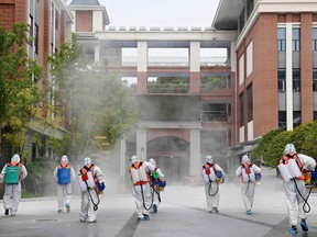 Workers in protective suits disinfect the compound of a primary school before schools reopen for the upcoming semester, following the COVID-19 outbreak in Wuhan, Hubei province, China Aug. 25, 2021.