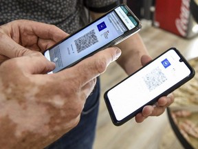 A person uses a pass verification application on a smartphone to check a health pass displayed on a smartphone.