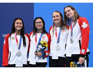 Silver medallists (from R) Canada's Penny Oleksiak, Canada's Rebecca Smith, Canada's Margaret Macneil and Canada's Kayla Sanchez pose on the podium after the final of the women's 4x100m freestyle relay swimming event during the Tokyo 2020 Olympic Games at the Tokyo Aquatics Centre in Tokyo on July 25, 2021. (Photo by Jonathan NACKSTRAND / AFP)
