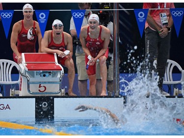 Canada's Taylor Ruck, Canada's Sydney Pickrem aand Canada's Margaret Macneil cheer on teammate Canada's Kayla Sanchez to win a heat for the women's 4x100m medley relay swimming event during the Tokyo 2020 Olympic Games at the Tokyo Aquatics Centre in Tokyo on July 30, 2021. (Photo by Oli SCARFF / AFP)