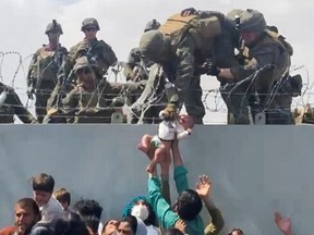 A baby is handed over to the American army over the perimeter wall of the airport for it to be evacuated, in Kabul, Afghanistan, Aug. 19, 2021.