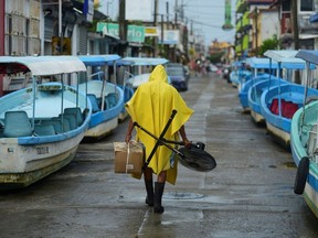 A man carries a fan and a box while walking past tourist boats that were moved from the water for safety as Hurricane Grace gathered more strength before reaching land, in Tecolutla, Mexico August 20, 2021.