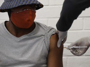 In this file photo taken on June 24, 2020 One of the first South African Oxford vaccine trialists looks on as a medical worker injects him with the clinical trial for a potential vaccine against the COVID-19 coronavirus at the Baragwanath hospital in Soweto, South Africa.