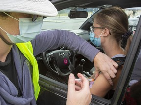 Savannah Vince receives her COVID-19 vaccine from Dr. Veronica Legnini during a drive-thru clinic at Richardson stadium in Kingston, Ont., on July 2, 2021.