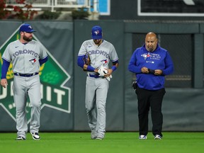 Lourdes Gurriel Jr. walks to the dugout with a medical trainer and coach John Schneider  after injuring his hand in the fifth inning of the game against the Minnesota Twins at Target Field on September 23, 2021 in Minneapolis.
