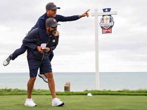 Team USA’s Justin Thomas points toward the green as he jumps on the back of Michael Greller, caddie for Jordan Spieth, on the fourth tee prior to the 43rd Ryder Cup at Whistling Straits in Kohler, Wisc.