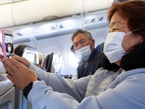 A passenger takes a selfie while wearing a protective mask in a airplane before take-off at the Phoenix International Airport on March 14, 2020.