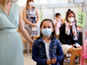 Children and parents wearing protective face masks wait for a COVID-19 rapid antigen test in a primary school, as Austrian schools open for pupils after summer holidays, in Vienna, Austria, Monday, Sept. 6, 2021.