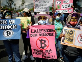 A person holds a sign that reads "The Bitcoin bill must be repealed, it will bring more corruption and poverty," as people participate in a protest against the use of Bitcoin as legal tender, in San Salvador, El Salvador, Sept. 7, 2021.