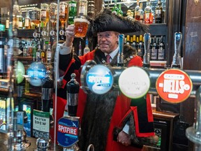 Lord Mayor of London William Russell, poses for a photograph with a pint of beer behind the bar inside the re-opened 'Old Dr Butlers Head' pub in London.