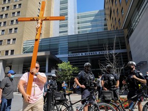 A protester carries a crucifix during an anti-vaccine mandate protest outside Toronto General Hospital in Toronto, Sept. 13, 2021.