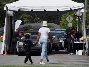 A woman holds a child's hand as they arrive at a COVID-19 drive-through testing site at Frederick Douglass High School in Atlanta, Aug. 30, 2021.