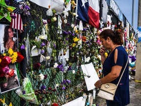 In this file photo taken on July 24, 2021 a woman prays as she visits a makeshift memorial where the partially collapsed Champlain Towers South building stood in Surfside, Florida.