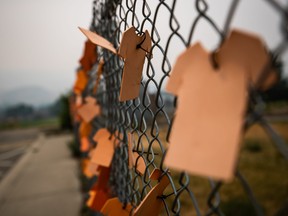 Cutouts of orange T-shirts are hung on a fence outside the former Kamloops Indian Residential School, in Kamloops, B.C., on Thursday, July 15, 2021. THE CANADIAN PRESS/Darryl Dyck