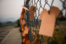 Cutouts of orange T-shirts are hung on a fence outside the former Kamloops Indian Residential School, in Kamloops, B.C., on Thursday, July 15, 2021. THE CANADIAN PRESS/Darryl Dyck