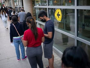 Voters are pictured on Sept. 20, 2021 as they line up at the Toroto Reference Library to cast ballots in Canada's federal election.