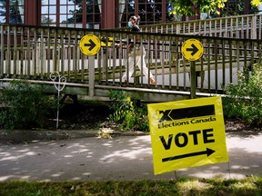 A woman walks by an Elections Canada sign at a polling station during in Canada's federal election, in Toronto September 20, 2021.