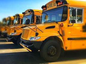 Row of yellow school buses parked with blue sky in background