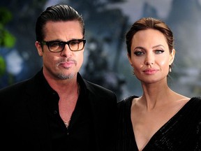 Angelina Jolie (R) poses for photographs along with Brad Pitt as they arrive for the premiere of the film 