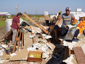 Corbert Barrios, right, and his wife, Anna Barrios, clean up their storm-damaged house after Hurricane Ida on September 4, 2021 in Grand Isle, Louisiana.